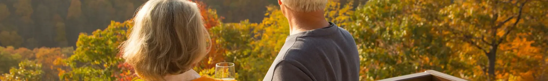 A couple enjoying a glass of wine on a terrace overlooking rolling countryside and colourful trees in New England during autumn