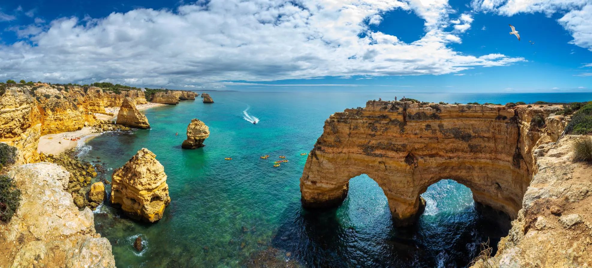 Scenic view of the coves, natural rock arches, and turquoise sea at Praia da Marinha on the Algarve, with rugged cliffs and clear water