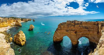 Scenic view of the coves, natural rock arches, and turquoise sea at Praia da Marinha on the Algarve, with rugged cliffs and clear water