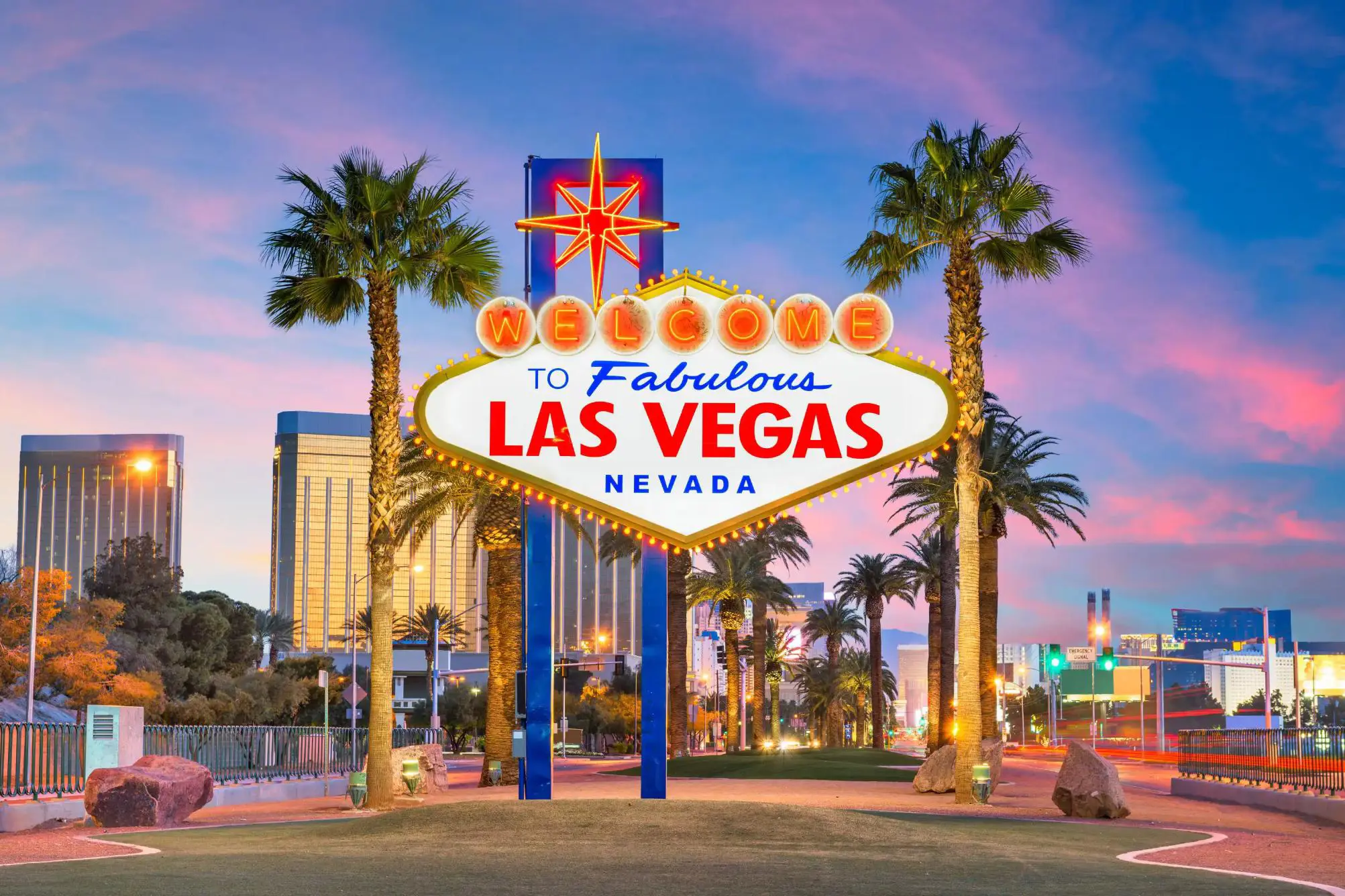 "Welcome to Fabulous Las Vegas, Nevada” sign at dusk, with palm trees and city lights in the background