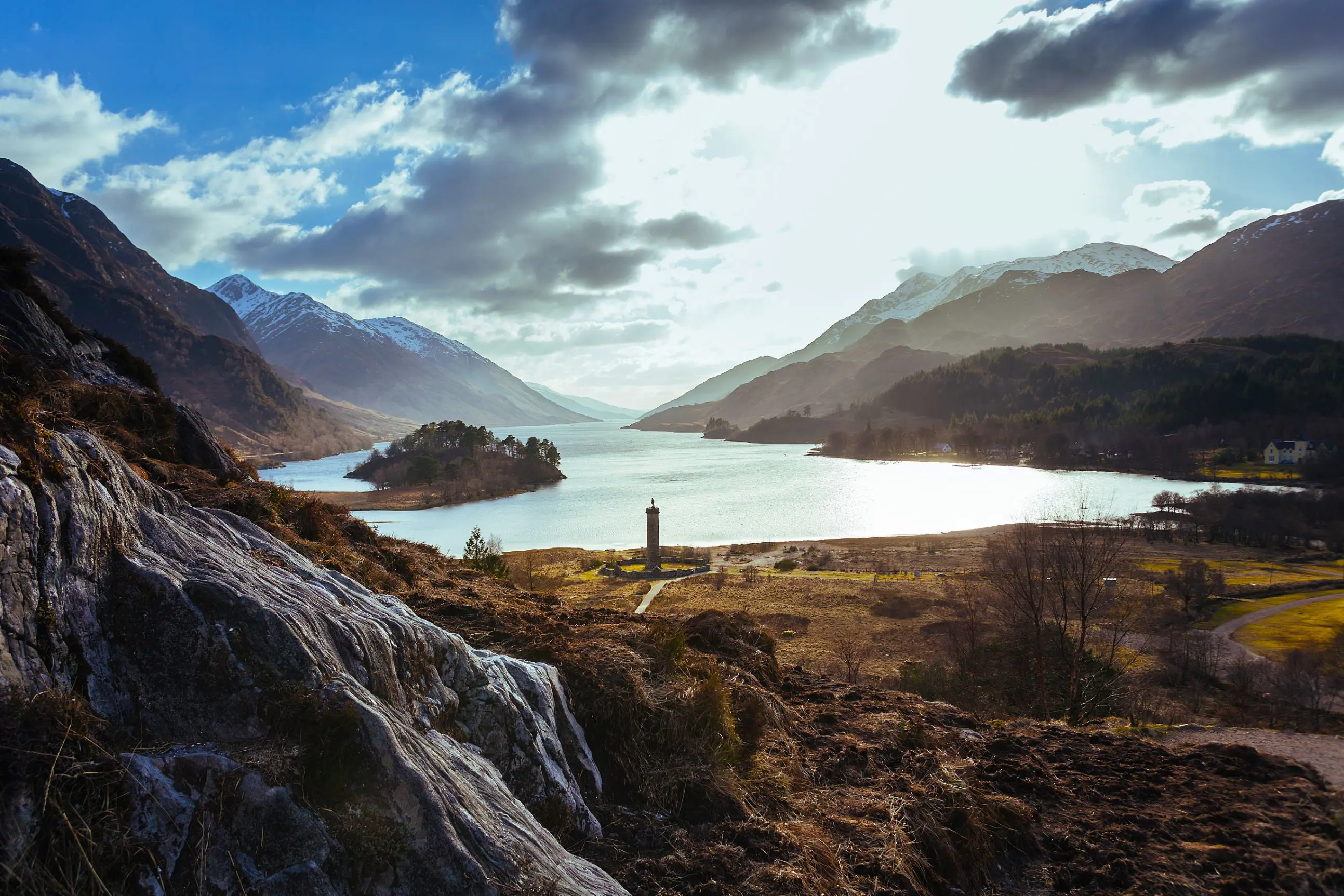 Zoomed out image of Glenfinnan Monument Scotland amongst the highlands with a view of Lock Shiel