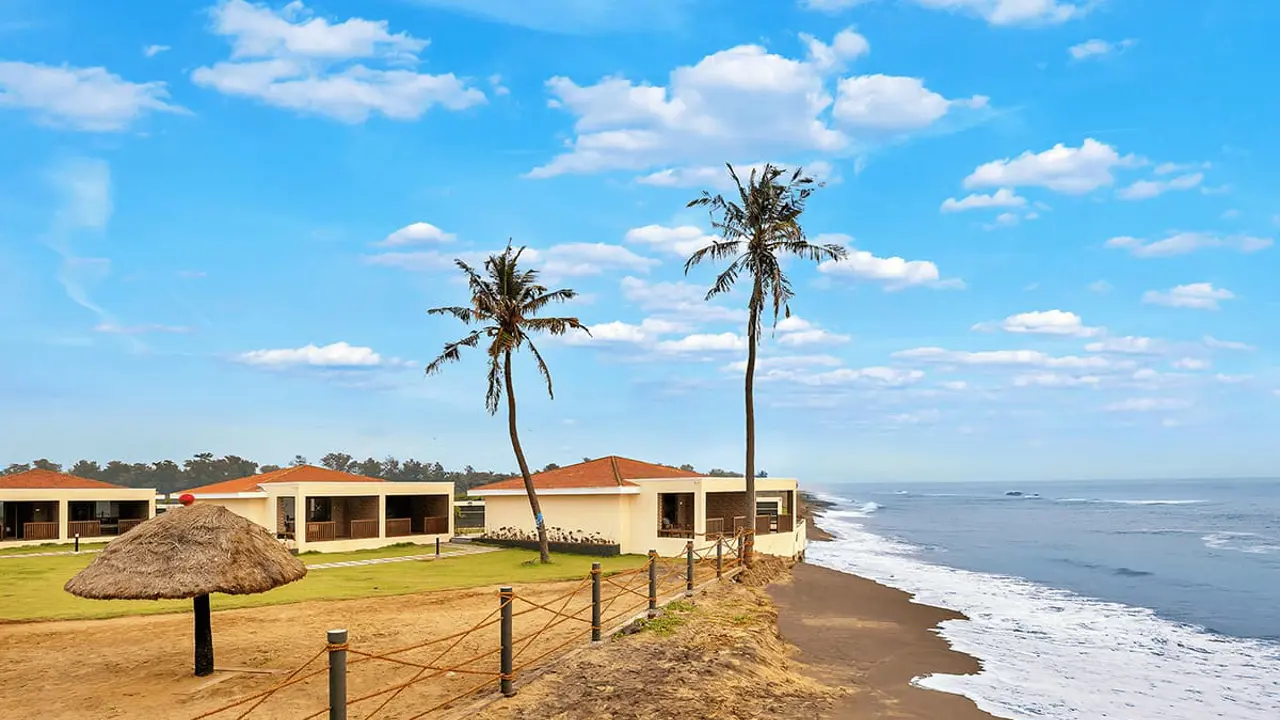 Beach villas directly on the shoreline at Welcomhotel by ITC Hotels in Mahabalipuram, under a partly sunny and cloudy sky