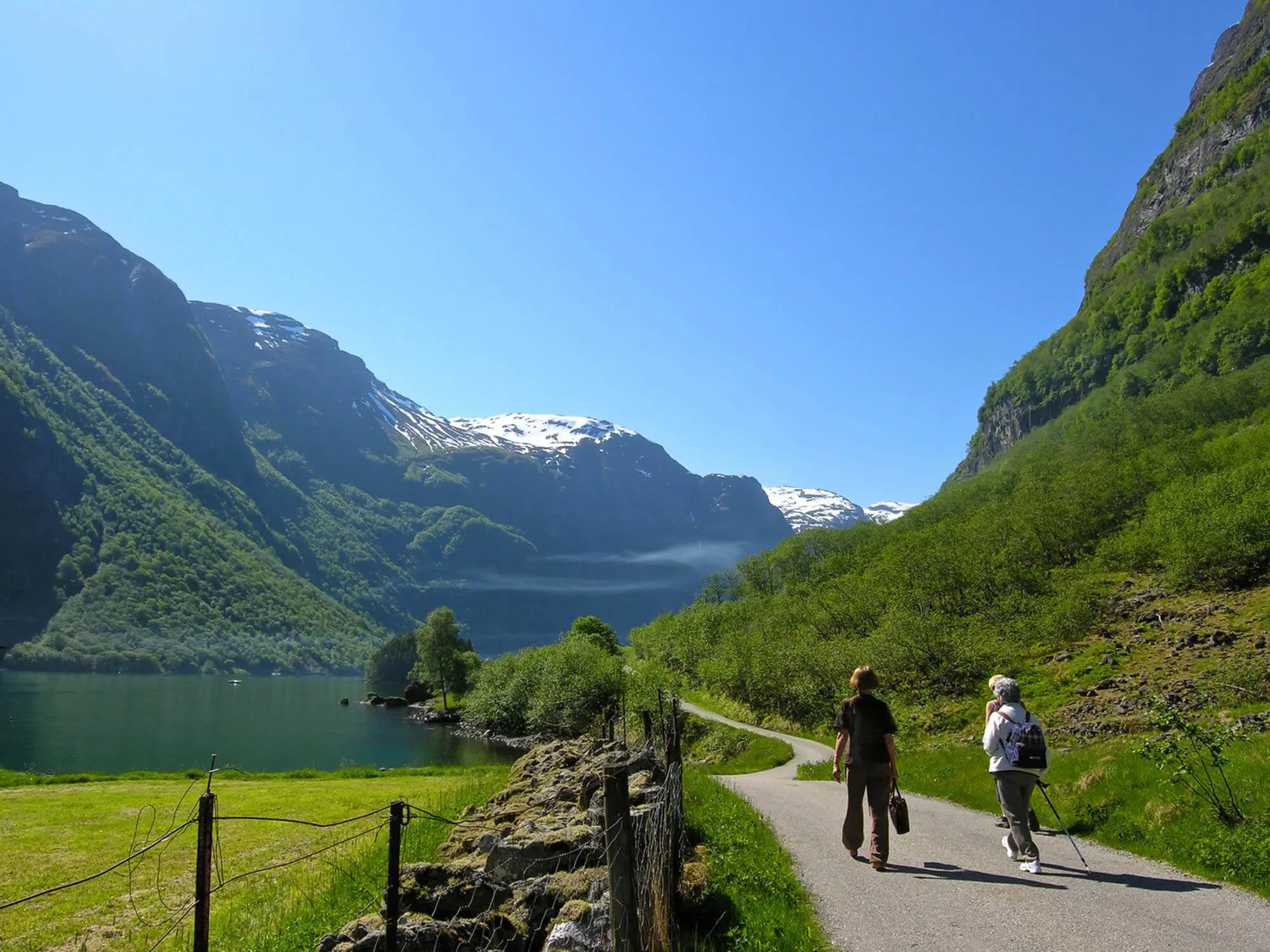 3 people hiking by The Naroyfjorden, with mountain in the distance