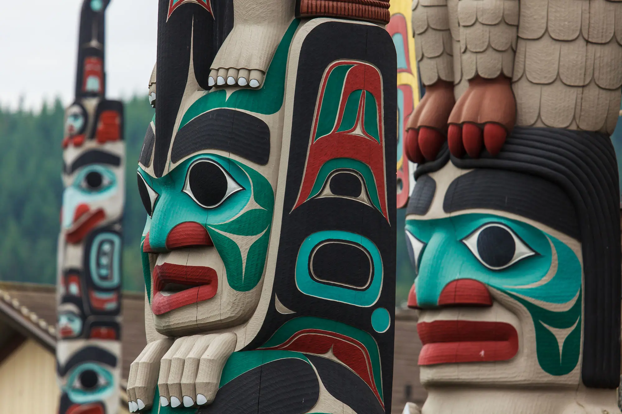 A close-up view of totem poles in Stanley Park, Canada, showcasing intricate carvings and vibrant colours representing Indigenous art and culture