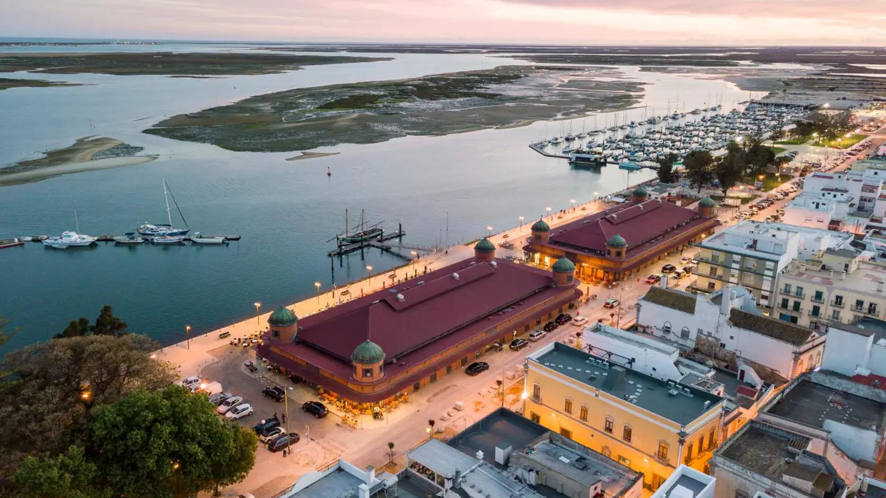 Coastline at sunset in Olhão on the Algarve, featuring a marina, small islands in view, and traditional buildings lit along the waterfront