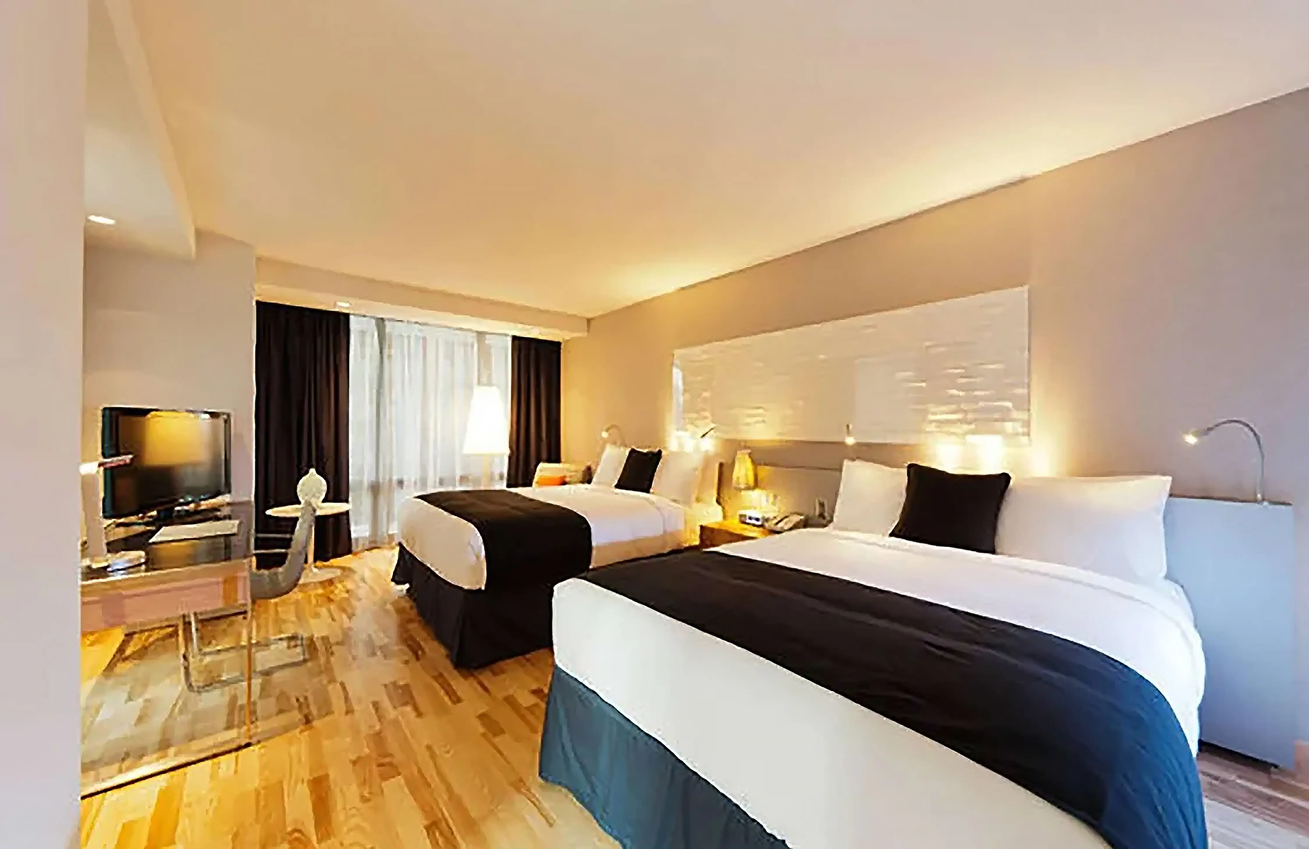 A twin room at Radisson Blu Aqua Hotel, Chicago, featuring two double beds with crisp white linens and a navy bed runner, sleek modern furnishings, floor-to-ceiling windows, and contemporary décor in neutral tones