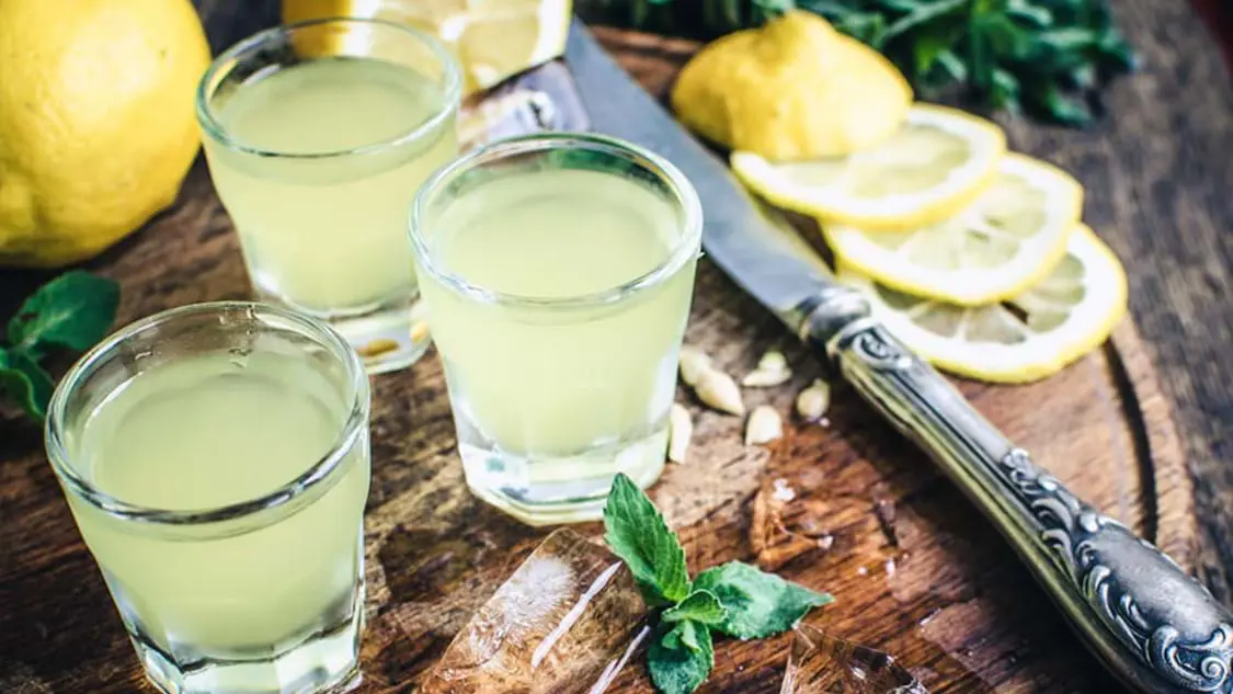 Close up of glasses of Limoncello, with lemons next to them