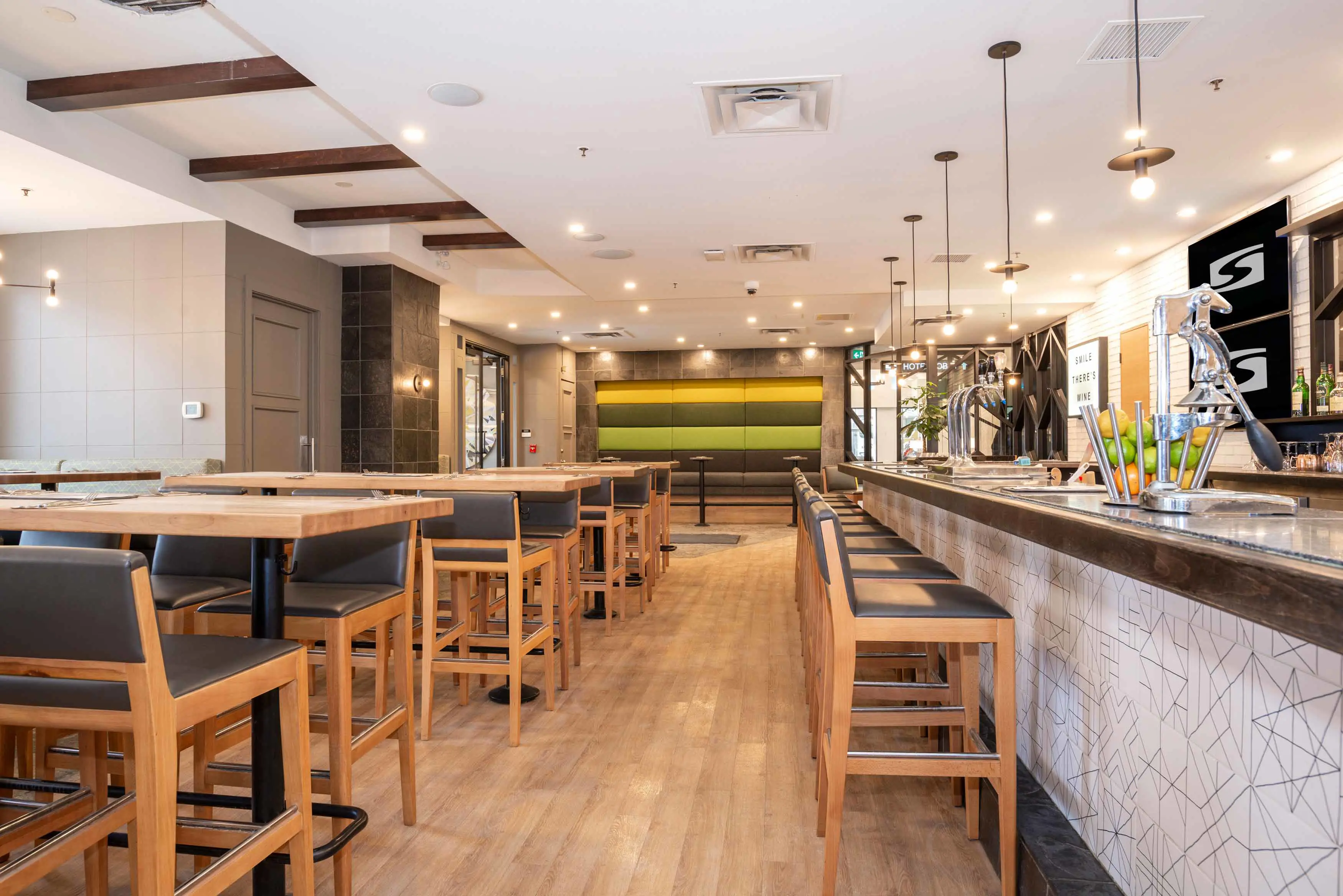 The bar at Sandman Signature Calgary Downtown, featuring a contemporary design with modern lighting, wood accents, and a relaxed, stylish atmosphere