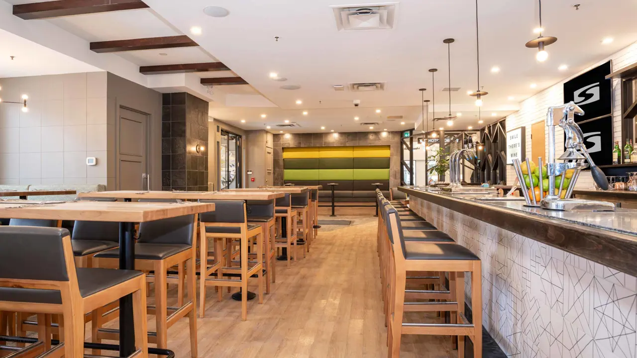 The bar at Sandman Signature Calgary Downtown, featuring a contemporary design with modern lighting, wood accents, and a relaxed, stylish atmosphere