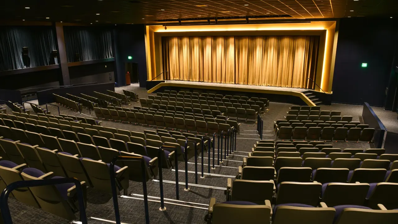 Private theatre at The Guest House at Graceland with tiered seating, a curtained stage, and ambient lighting for live shows and events