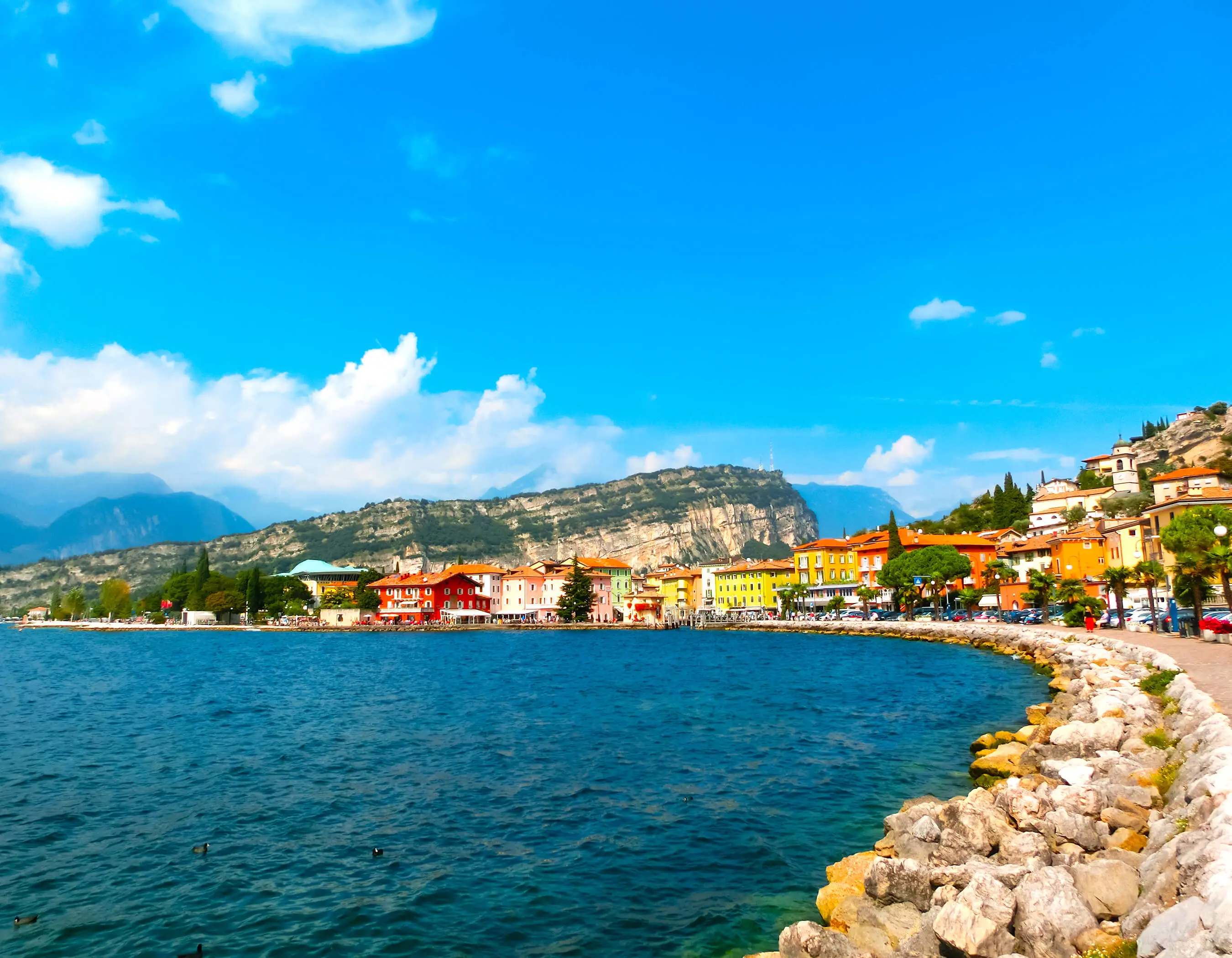 Waterfront in Torbole, Lake Garda, showing pavement and buildings and mountains in the distance