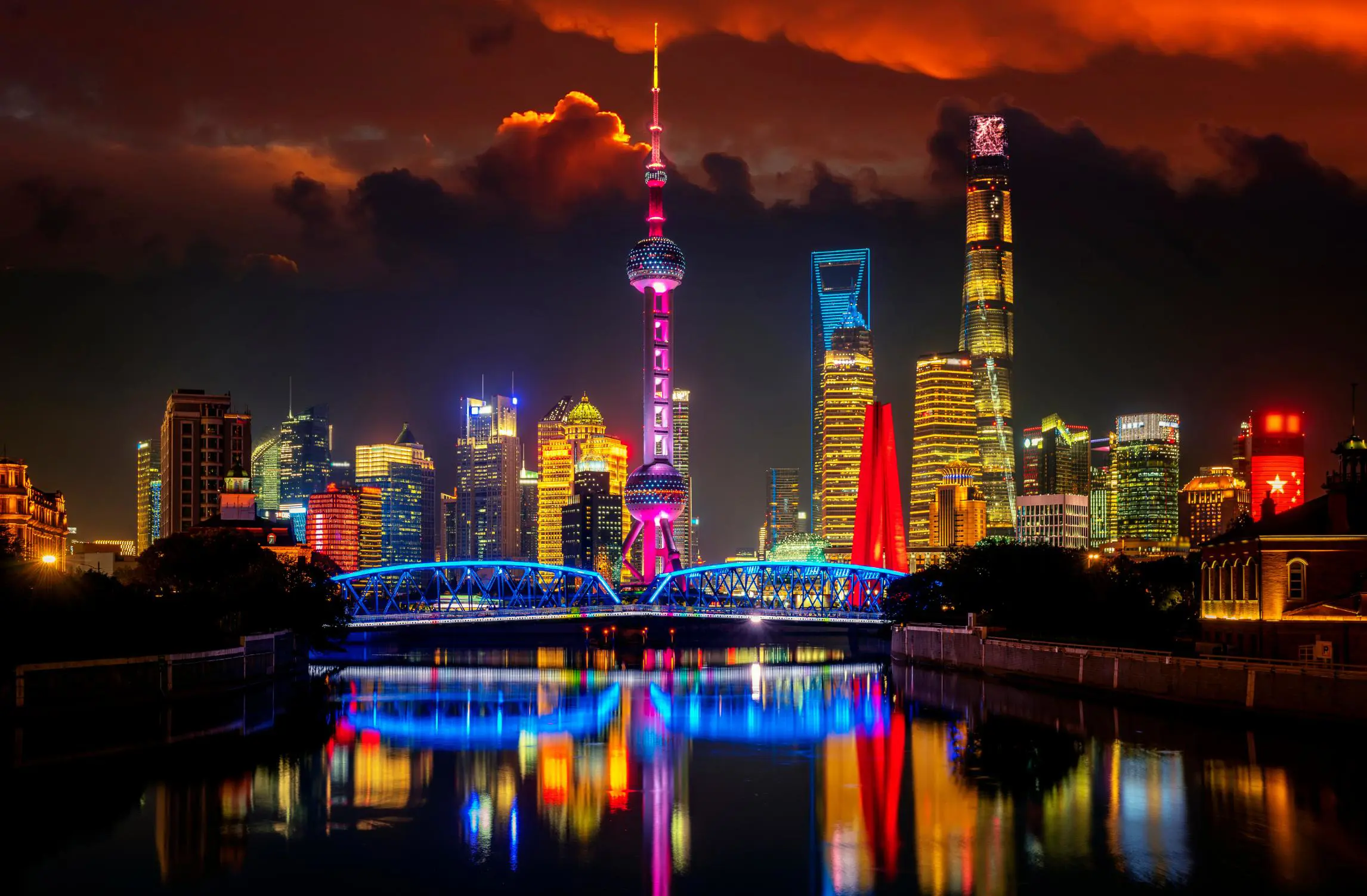 The Oriental Pearl Tower and modern skyscrapers lit in vibrant colours, reflected in the river at night in Shanghai, China