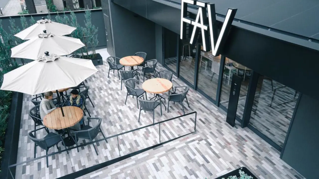 Outdoor terrace of FAV LUX Nagasaki with round tables, white umbrellas, and relaxed seating outside the entrance