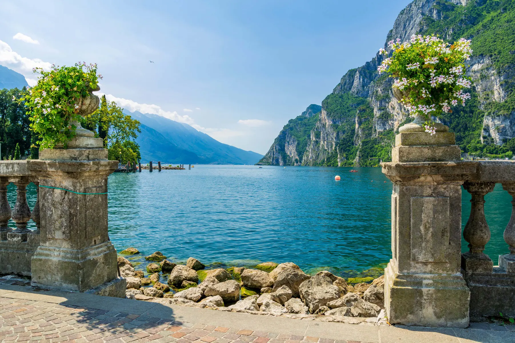 View of Riva Del Garda with bouquets of flowers in the forefront and mountains in the distance