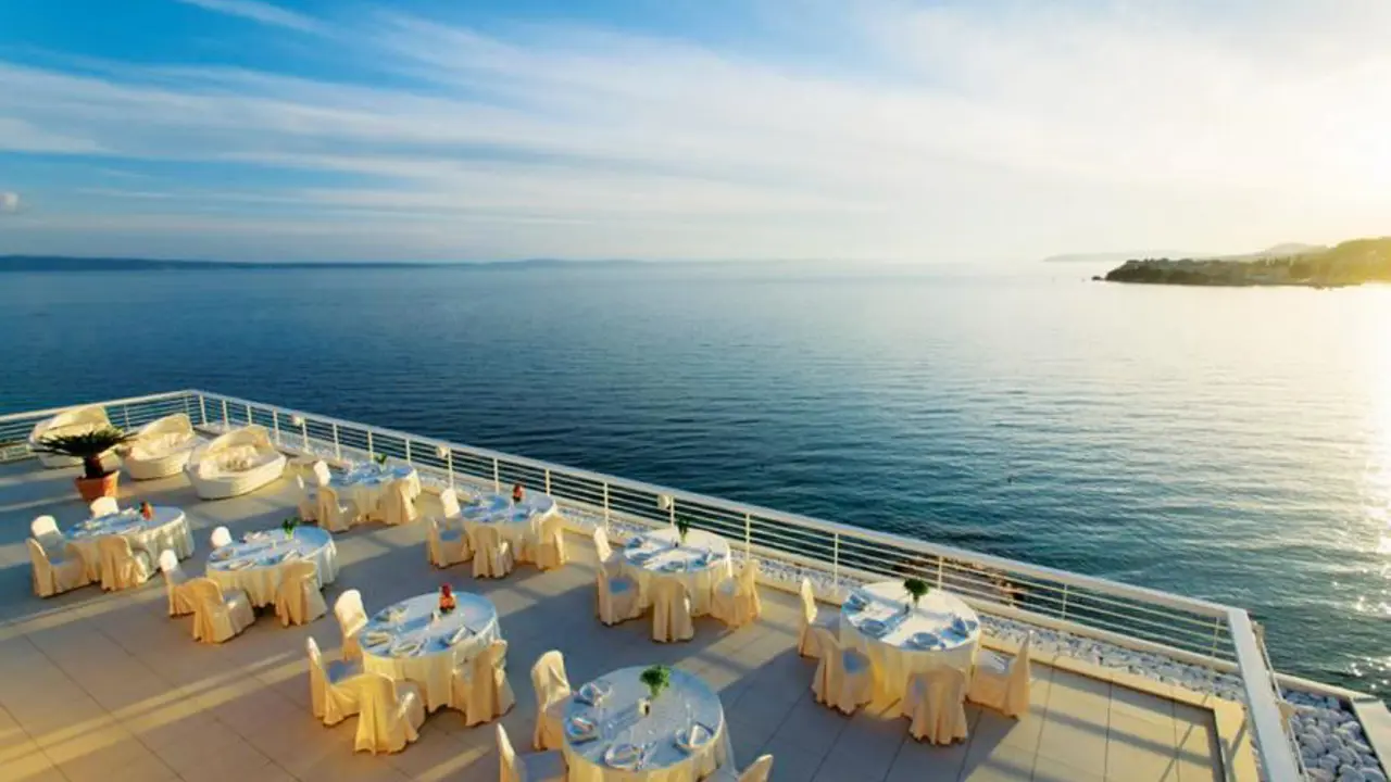 The dining terrace at Hotel Split, Podstrana, elegantly set with round tables and cream tablecloths, overlooking the Adriatic Sea