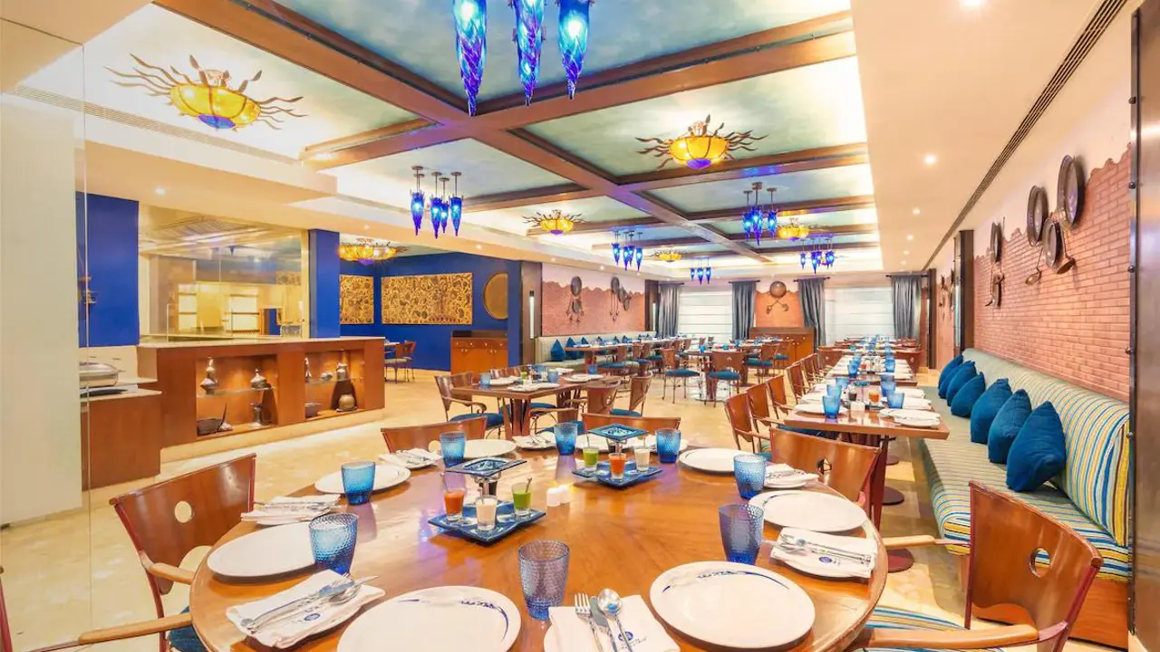A vibrant restaurant at the Radisson Hotel in Varanasi with wooden tables, blue lighting and decorative wall art
